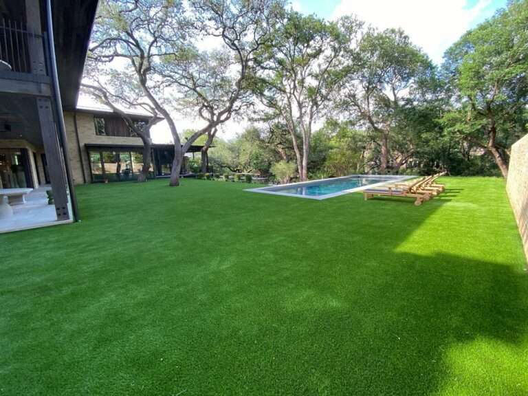 A pool in a backyard surrounded by artificial grass