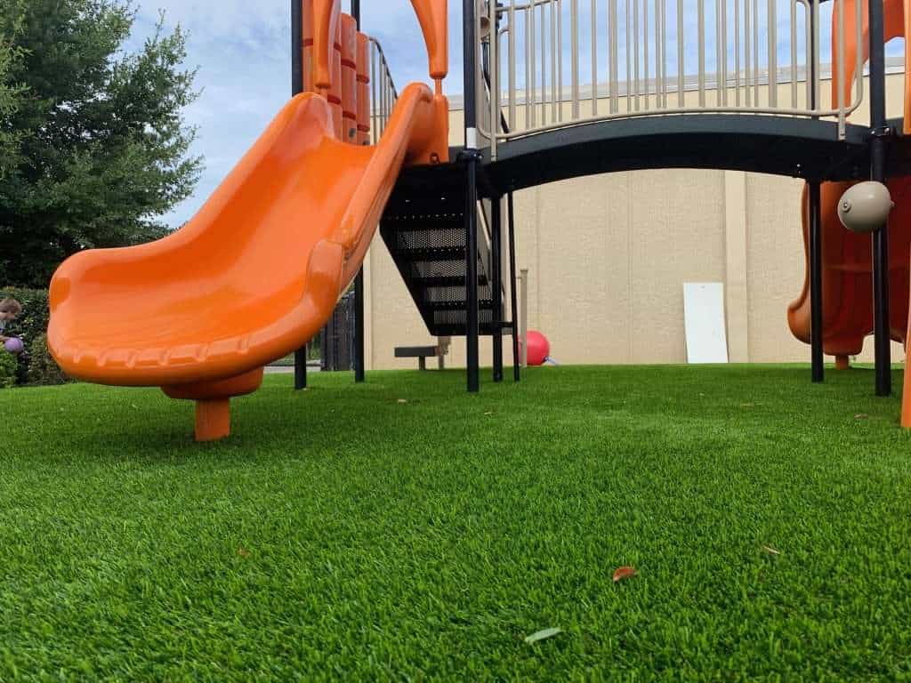 A playground with a slide on artificial turf