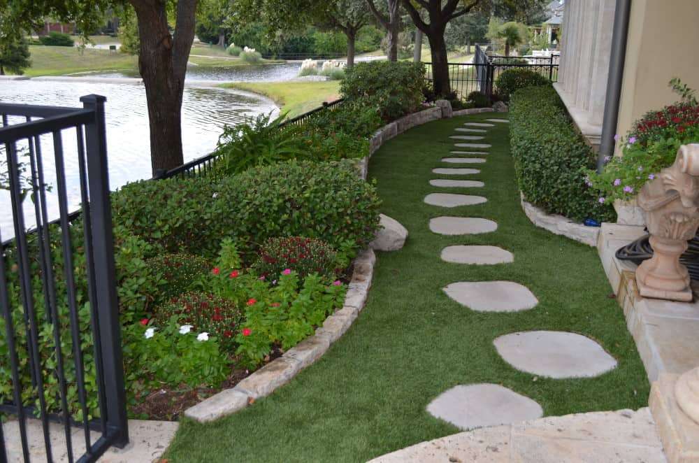 Stepping stones next to landscaped garden with artificial grass