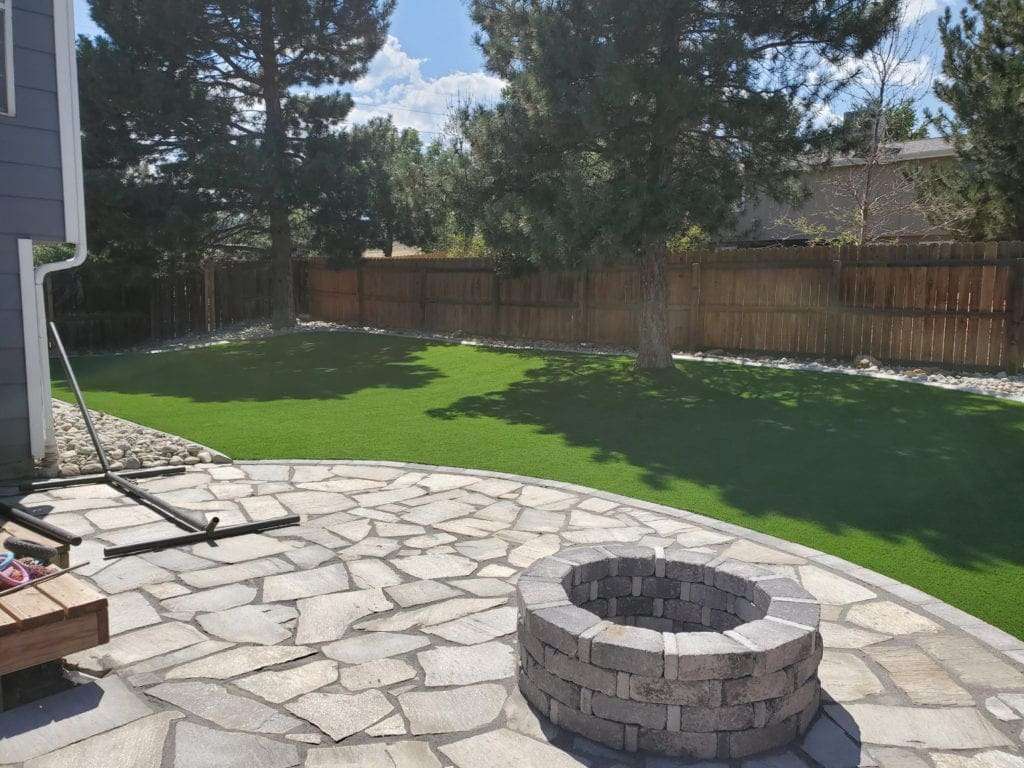Nice backyard with stone patio and firepit with artificial grass surround