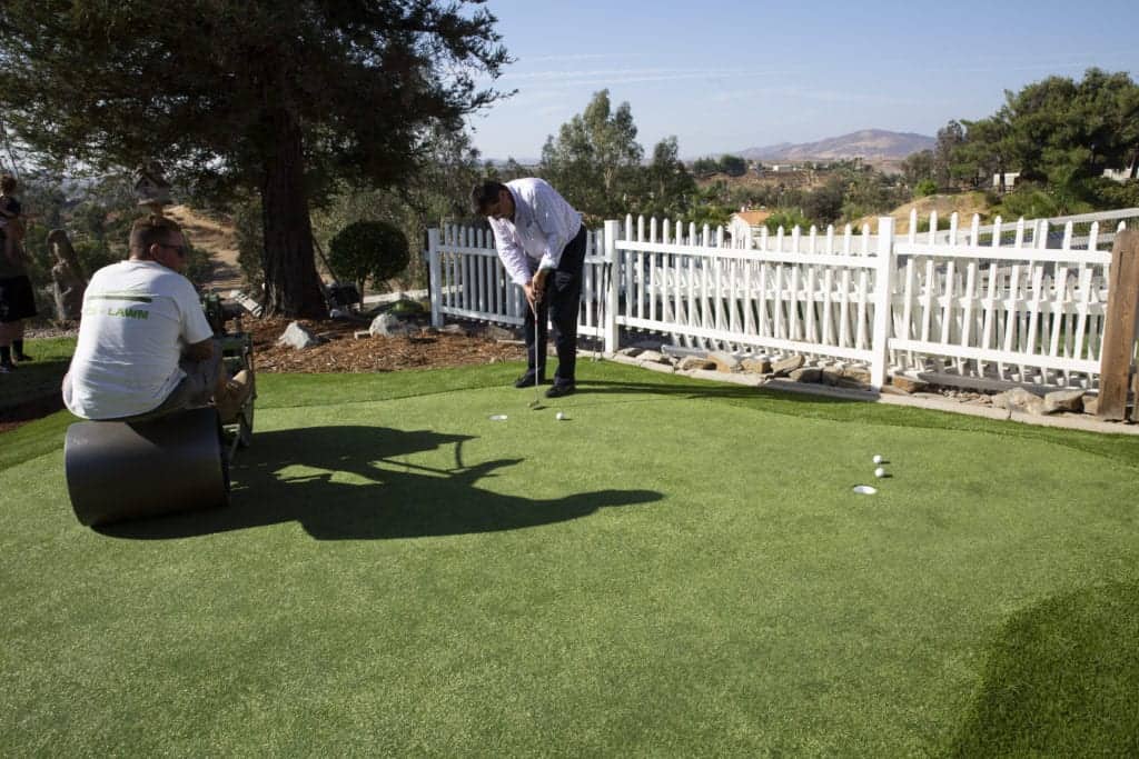 Artificial putting green being rolled by a riding roller.