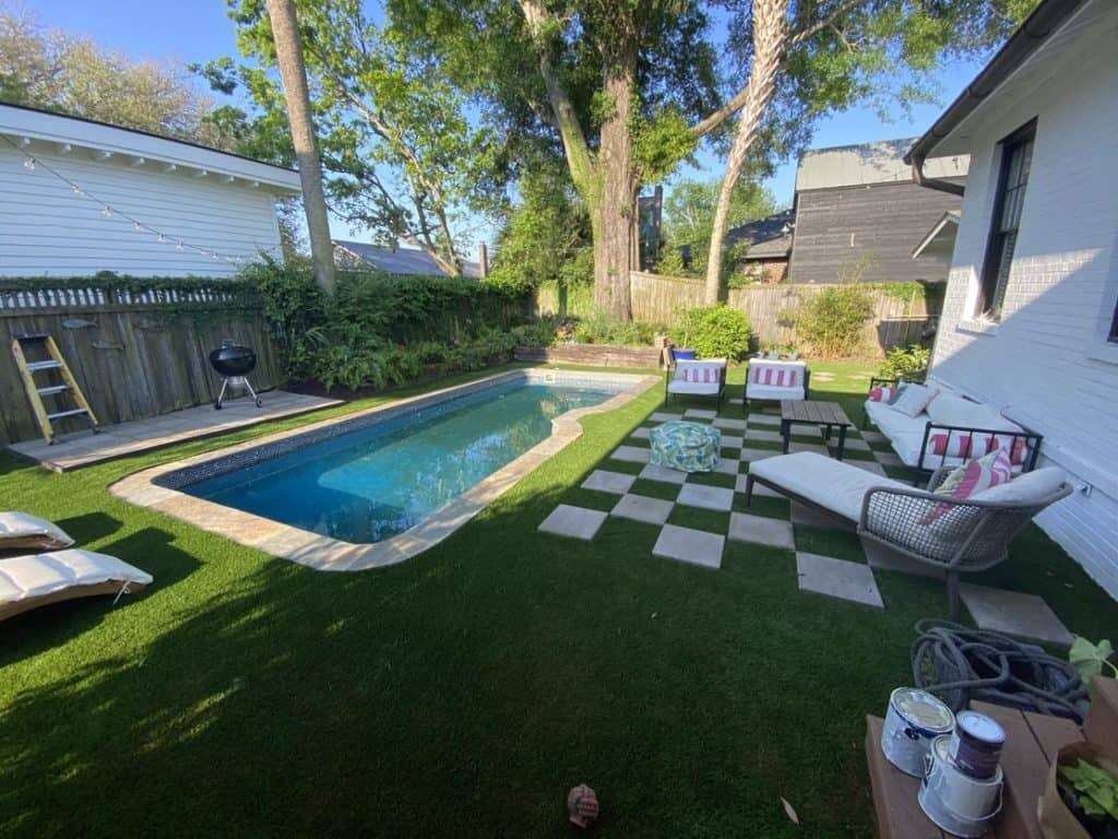 A pool in a backyard surrounded by artificial turf