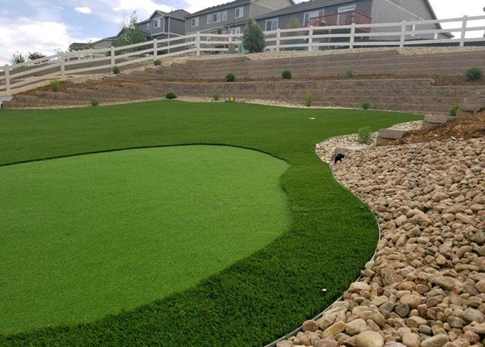 An artificial grass golf course with a white fence
