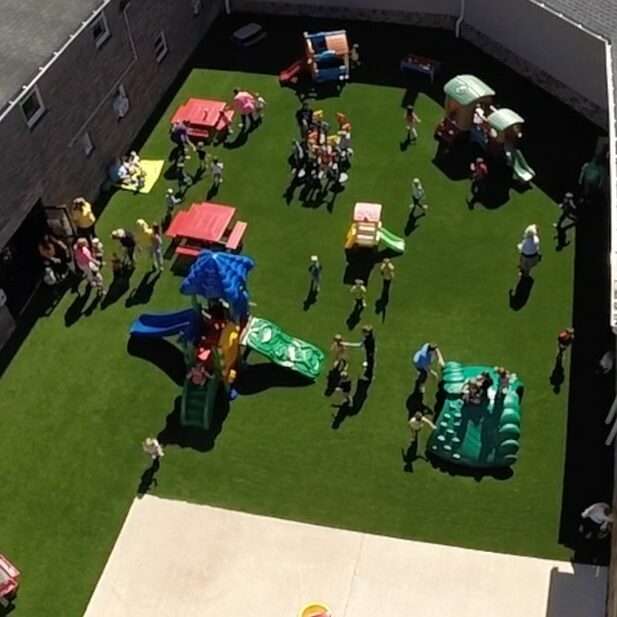 A group of kids playing on a playground on artificial grass