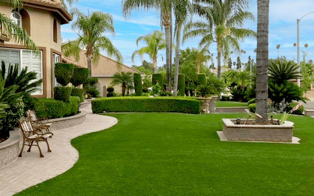 A artificial grass lawn with bushes and palm trees