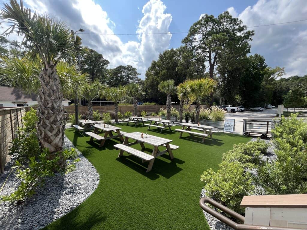 A picnic area with benches and trees on artificial turf