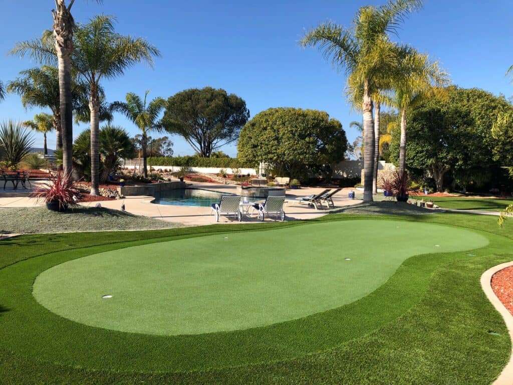 an artificial turf golf course with palm trees and a pool