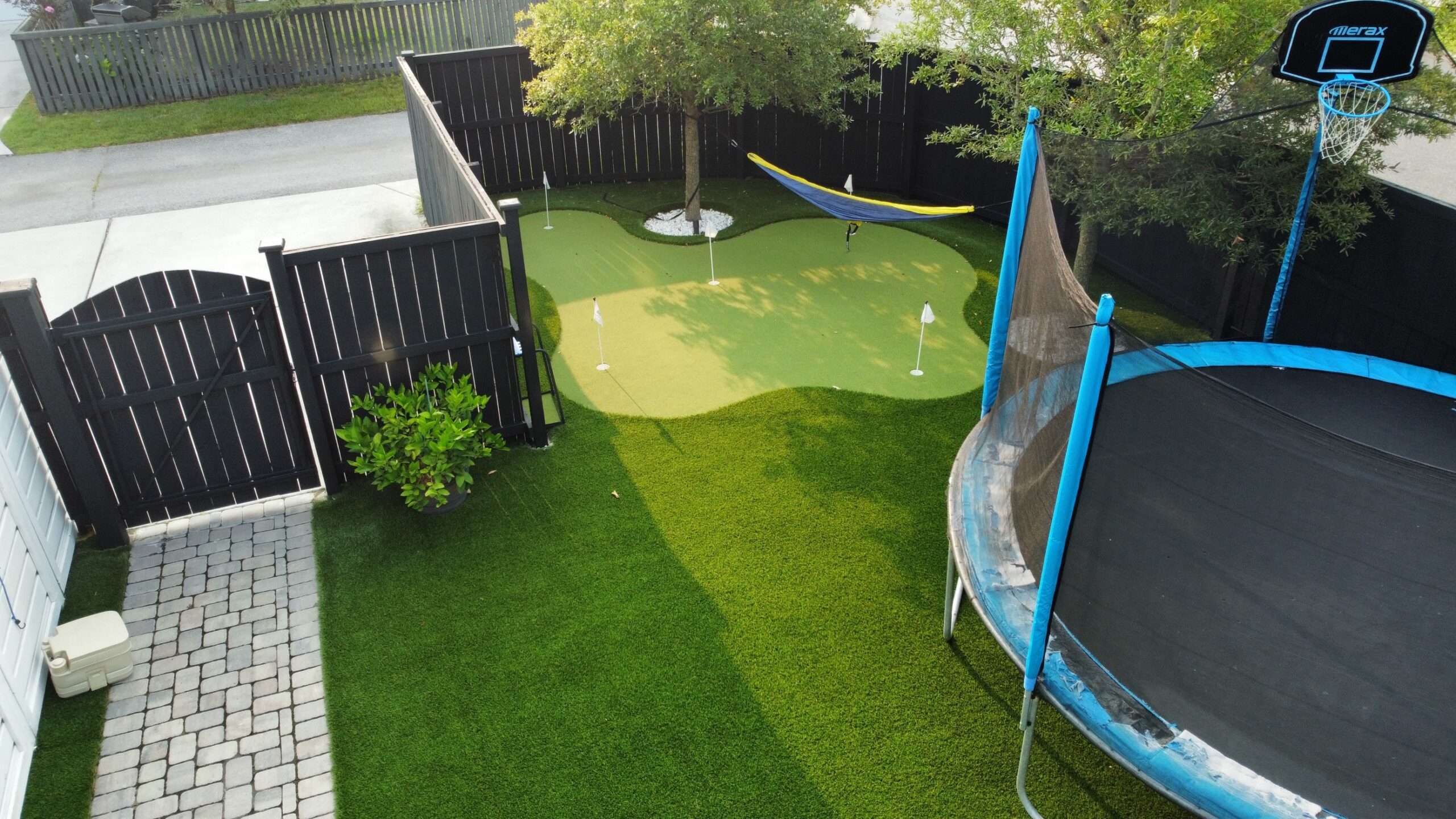 A backyard with a trampoline and an artificial grass golf course