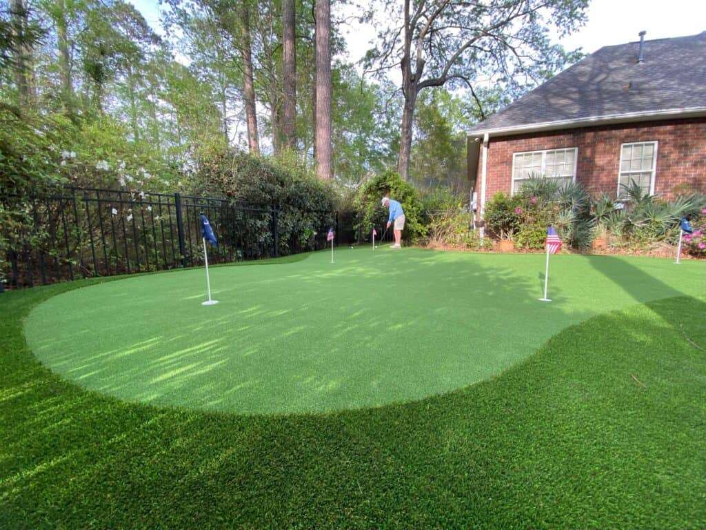 A person playing golf in their backyard on their artificial grass putting green