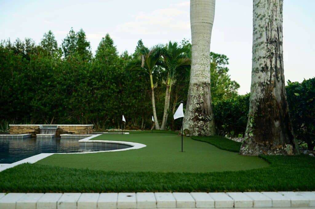 artificial turf putting green beside pool and trees