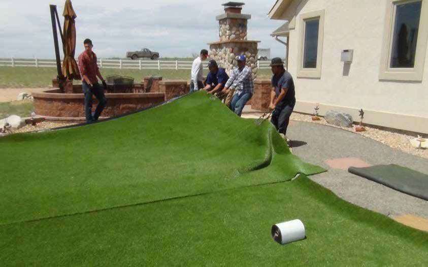 people laying out artificial turf