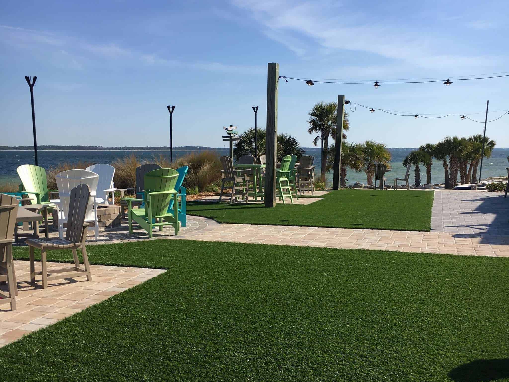 An artificial turf lawn with chairs and a walkway overlooking palm trees and ocean